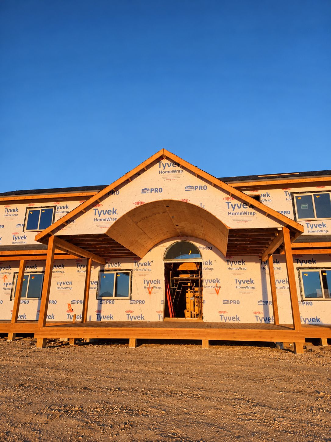 Arched porch framing over a wrapped house in golden light.