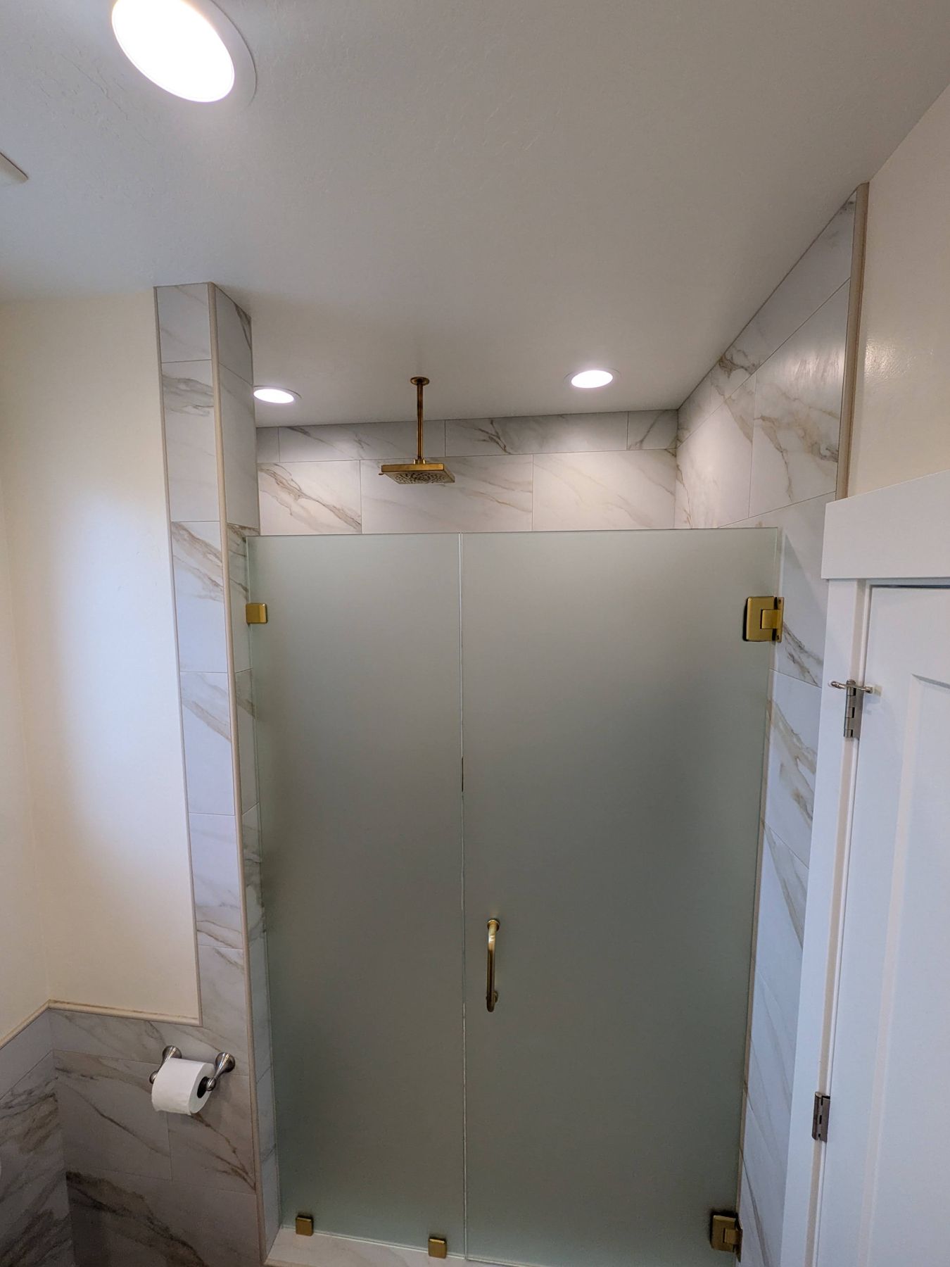 Tiled shower with frosted glass enclosure.