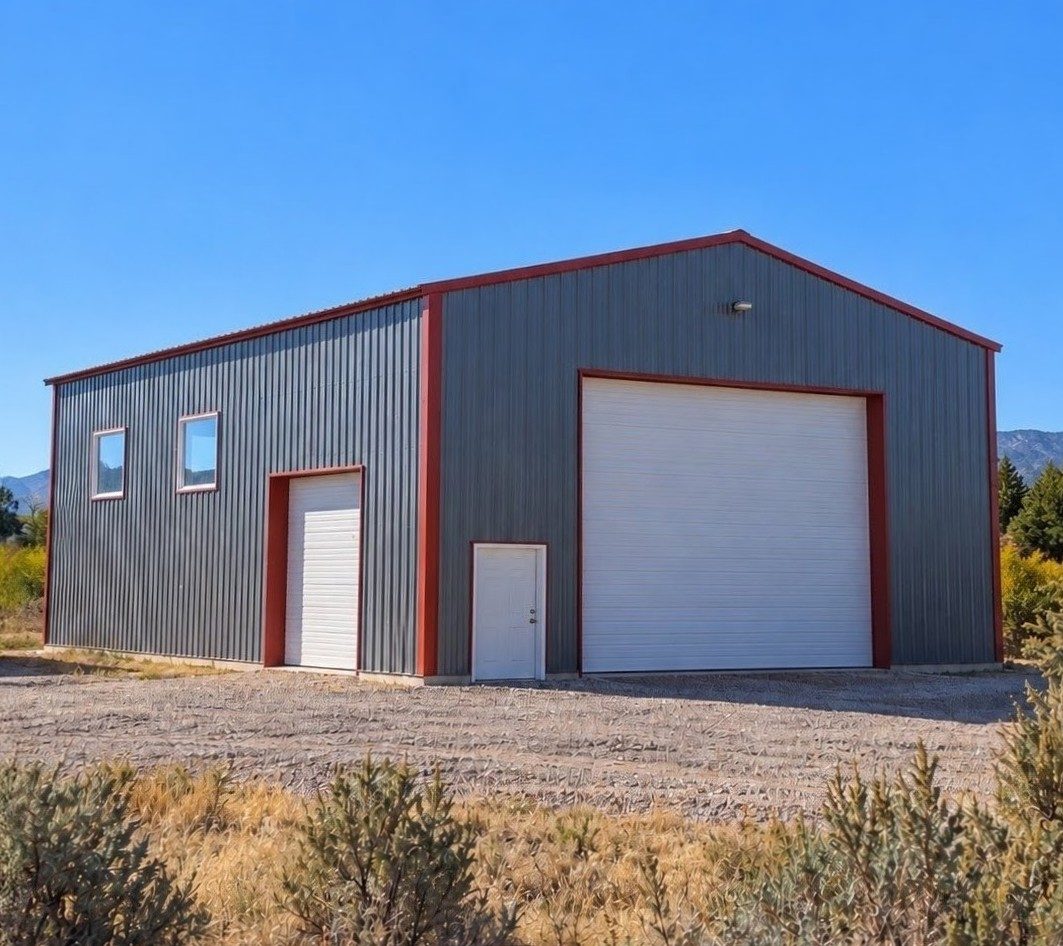 Gray metal shop with red trim, a large overhead door and a walk-in door.