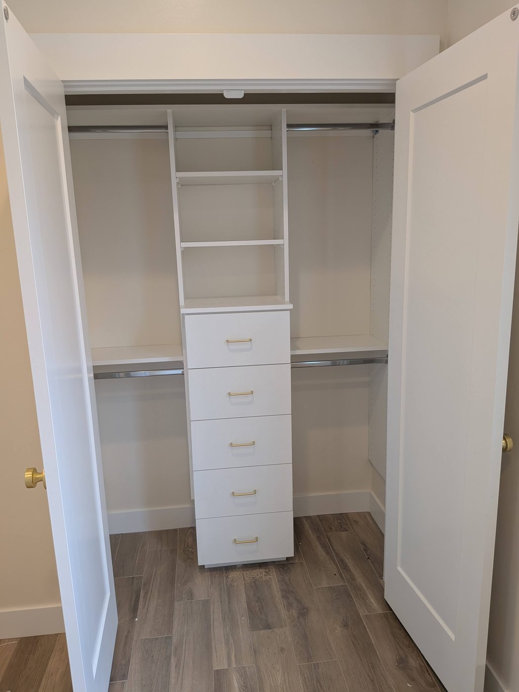 Reach-in closet with white shelving, hanging rod and drawers.