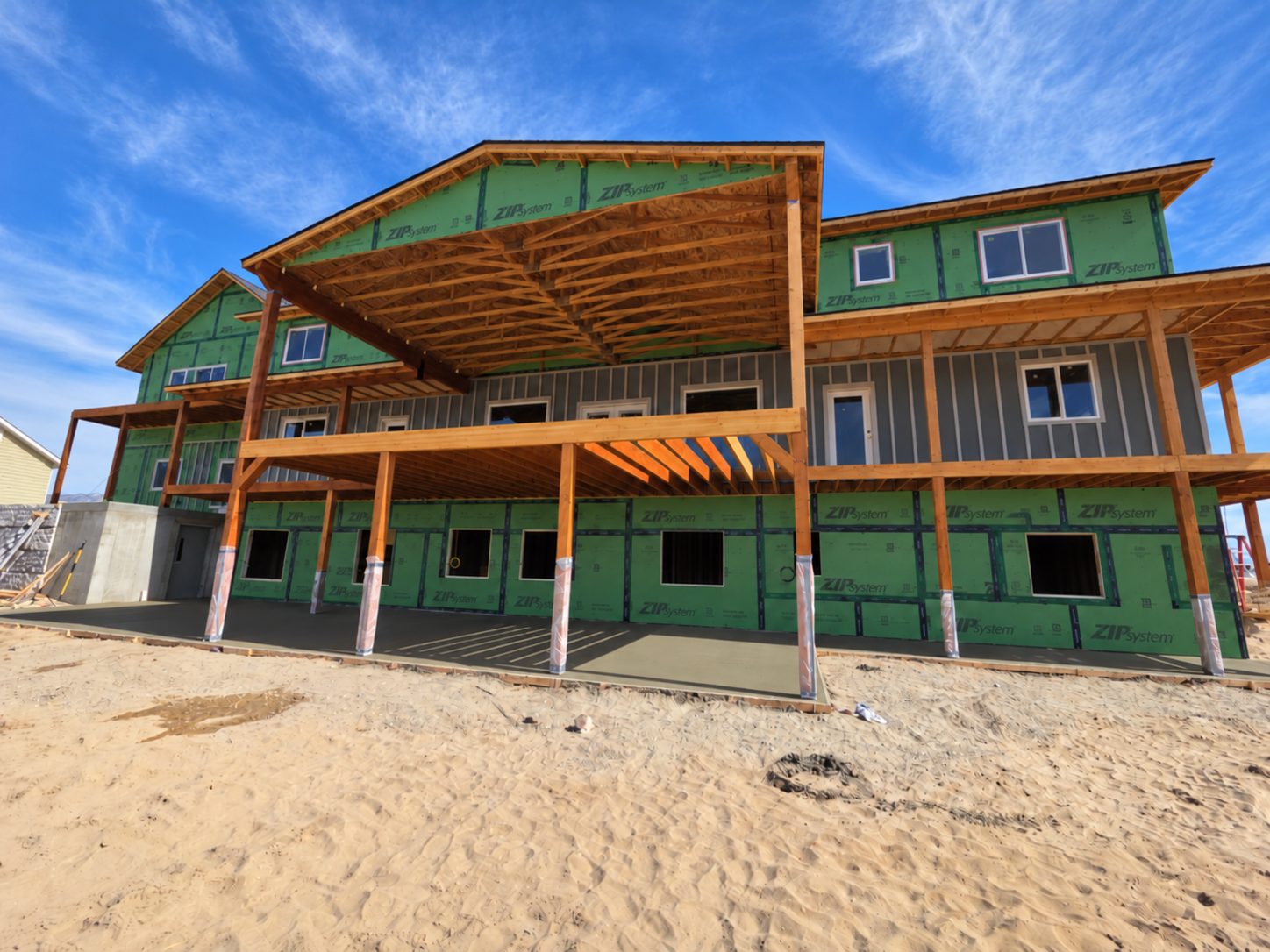Three-story home framed and sheathed with a large timber deck across the back.