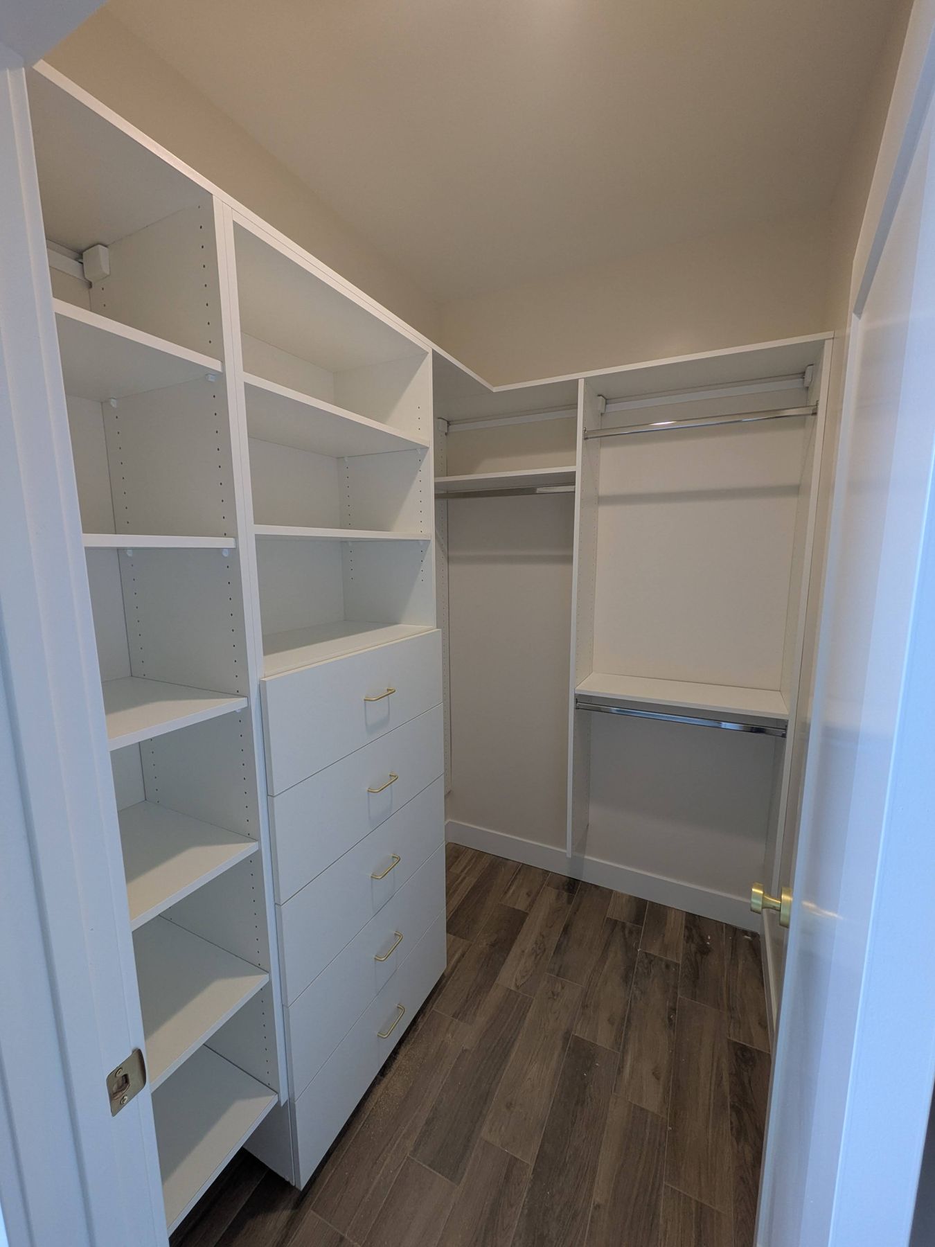Walk-in closet with white shelving, rods and drawers.