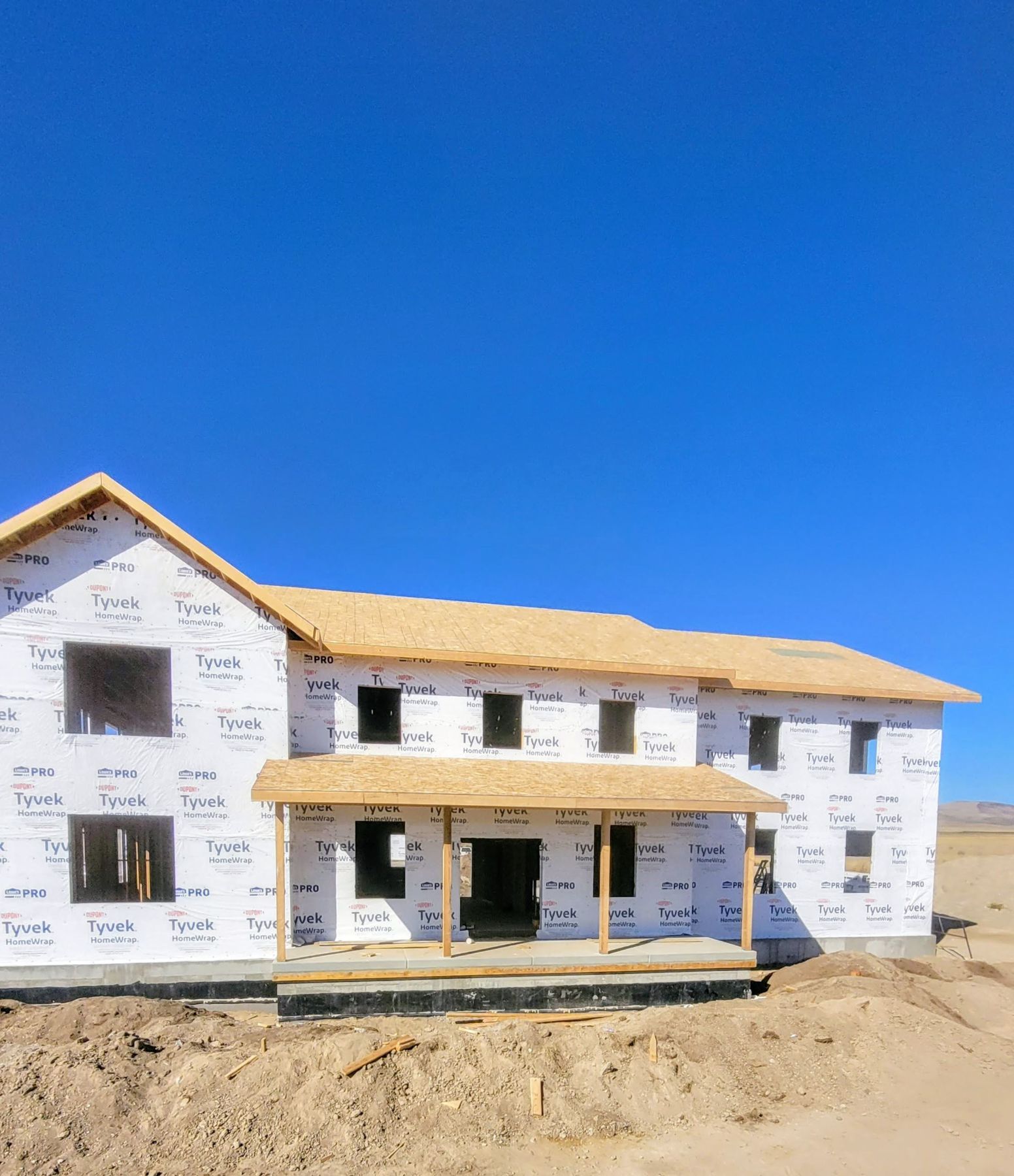 Two-story house in weather barrier wrap with roof sheathing.